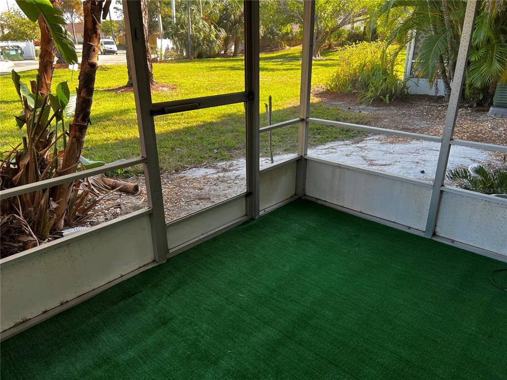 A screened-in porch features green artificial turf flooring and views of a grassy yard — 4112 HERON WAY UNIT B106, BRADENTON, FL