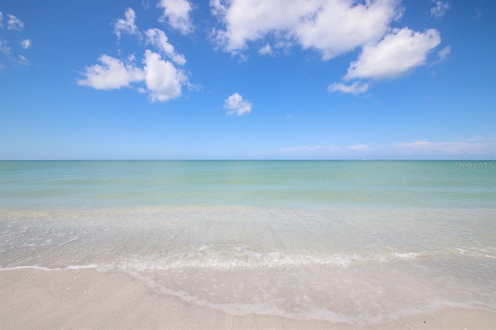 A view of a sandy beach meeting the calm ocean under a blue sky — 6920 PALM ISLAND DRIVE, PLACIDA, FL