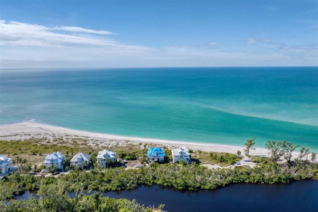 An aerial view shows several houses situated between a dark pond and a sandy beach — 6920 PALM ISLAND DRIVE, PLACIDA, FL