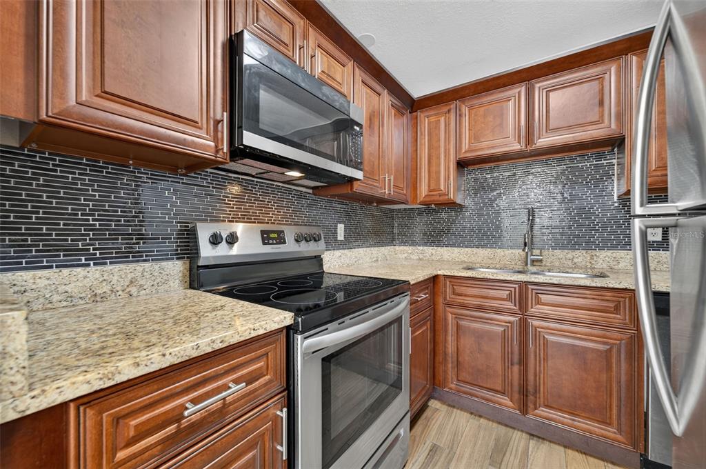 A wooden balcony with a gray door and sliding glass doors on a white building — 118 W AMERICA STREET UNIT 2, ORLANDO, FL