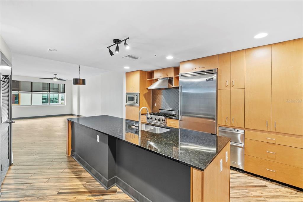 A kitchen features a large black island, light wood cabinetry, and stainless steel appliances — 1120 E KENNEDY BOULEVARD UNIT 618, TAMPA, FL
