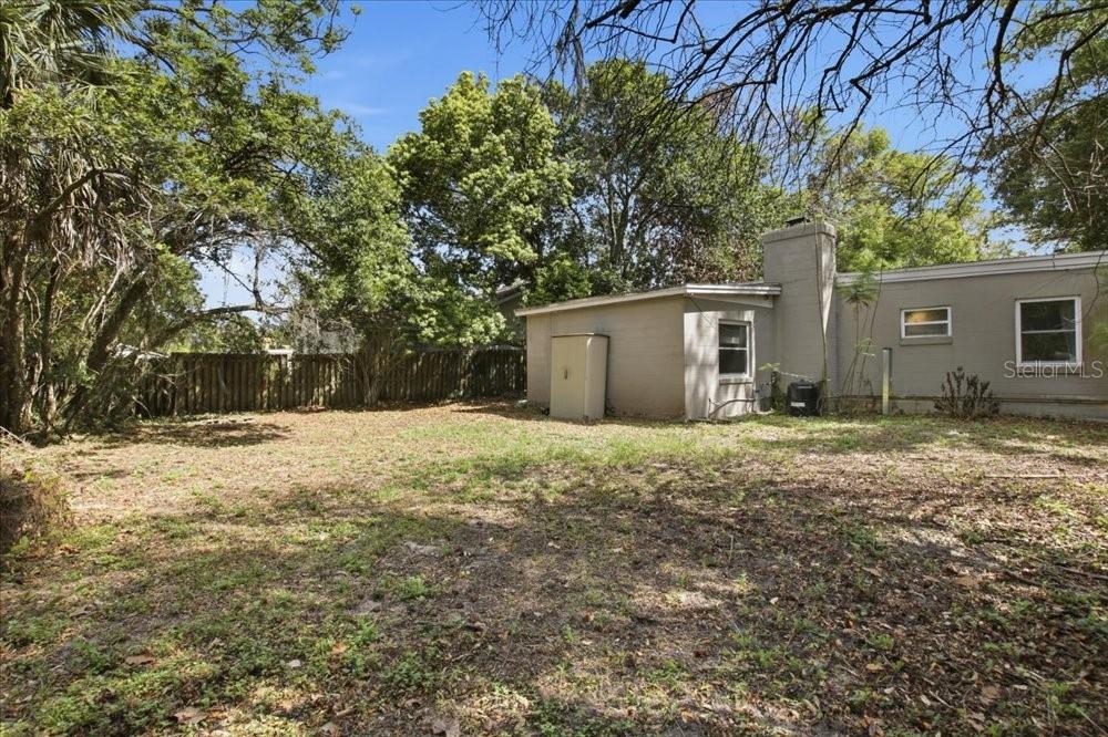 A backyard view of a single-story house with a chimney and a wooden fence — 1319 BESSMOR ROAD, WINTER PARK, FL