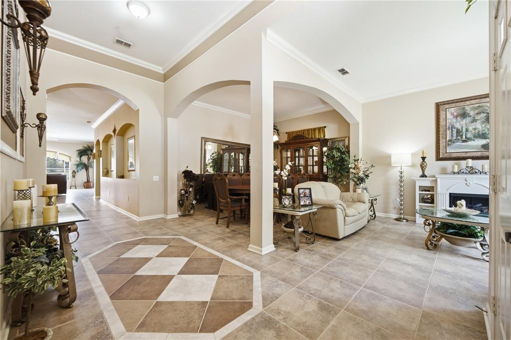 A tiled entryway leads into an open living room and dining area with arched architectural details — 25843 RISEN STAR DRIVE, WESLEY CHAPEL, FL