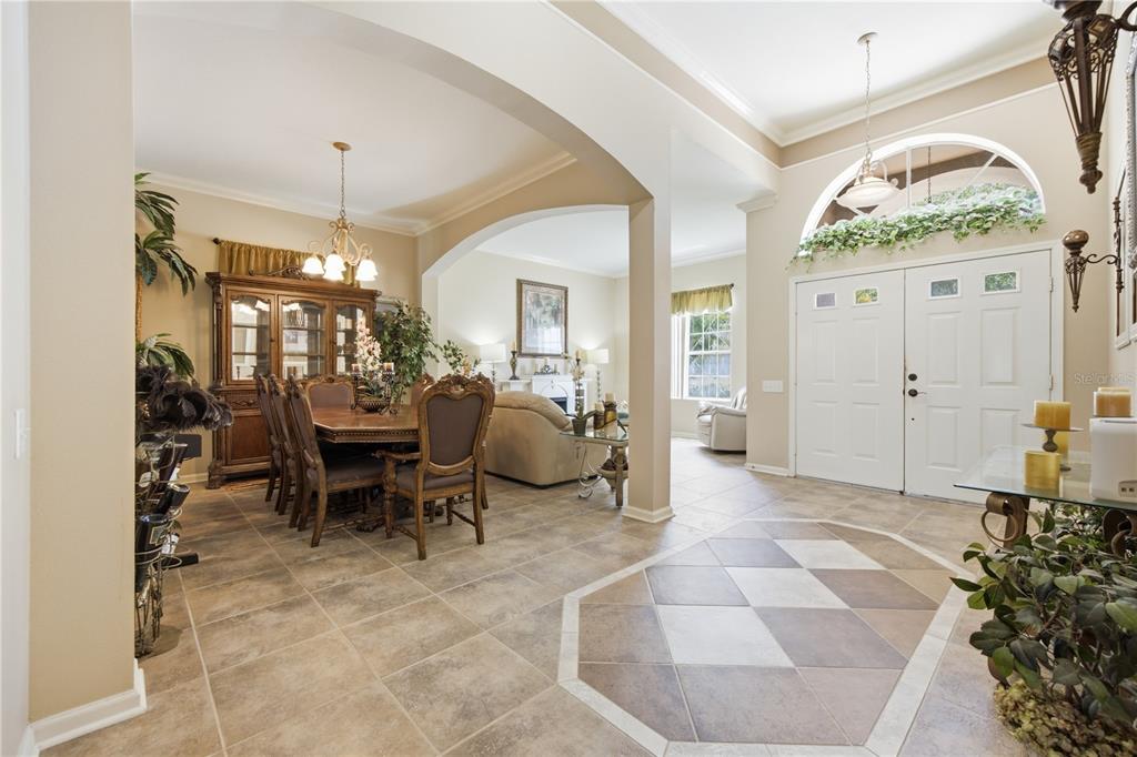 A tiled foyer leads into a dining room and living area with arched architectural details — 25843 RISEN STAR DRIVE, WESLEY CHAPEL, FL