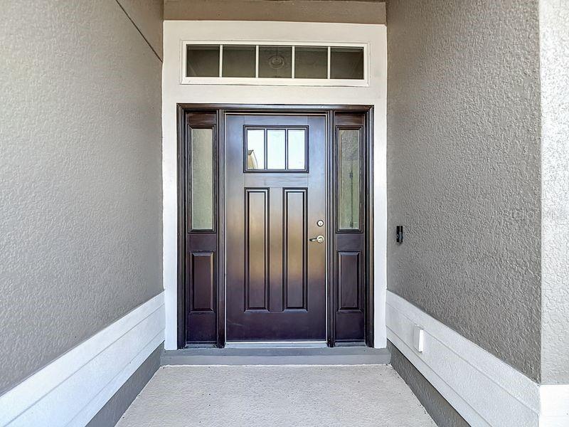 A dark brown front door with sidelights and a transom window sits in a recessed entryway — 12244 LOOPBACK DRIVE, SAN ANTONIO, FL