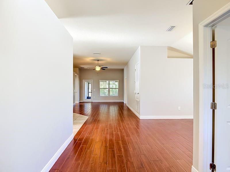 An interior view shows a hallway with wood-look flooring leading to a living area — 12244 LOOPBACK DRIVE, SAN ANTONIO, FL
