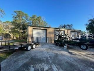 An exterior view of a metal warehouse building with two garage bays and a trailer — 1501 PEARL STREET, LONGWOOD, FL