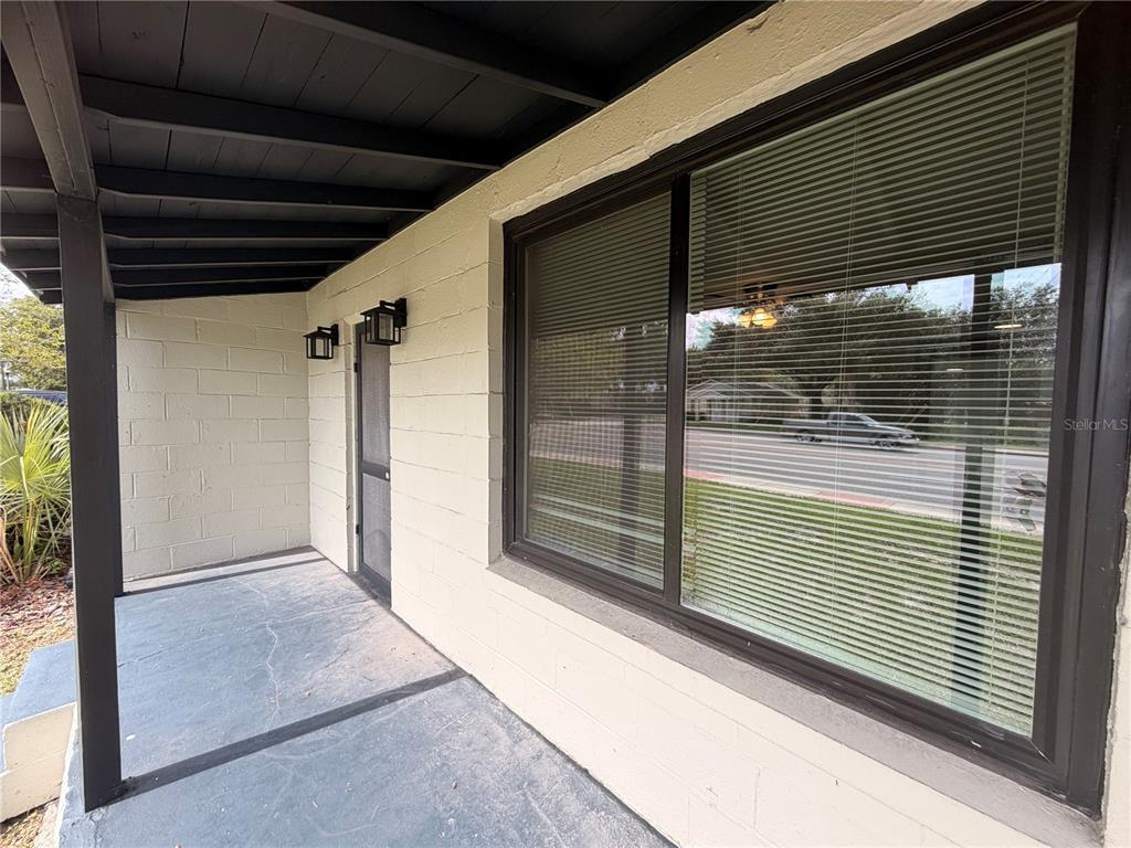 A covered porch features a painted concrete floor, a screen door, and a large window — 144 N PARK AVENUE, APOPKA, FL