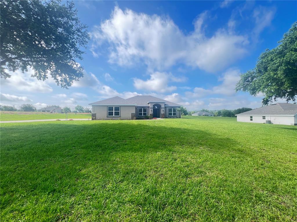 A single-story house with a gray roof sits on a large, grassy lot — 37298 HIDDEN VIEW CIRCLE, DADE CITY, FL