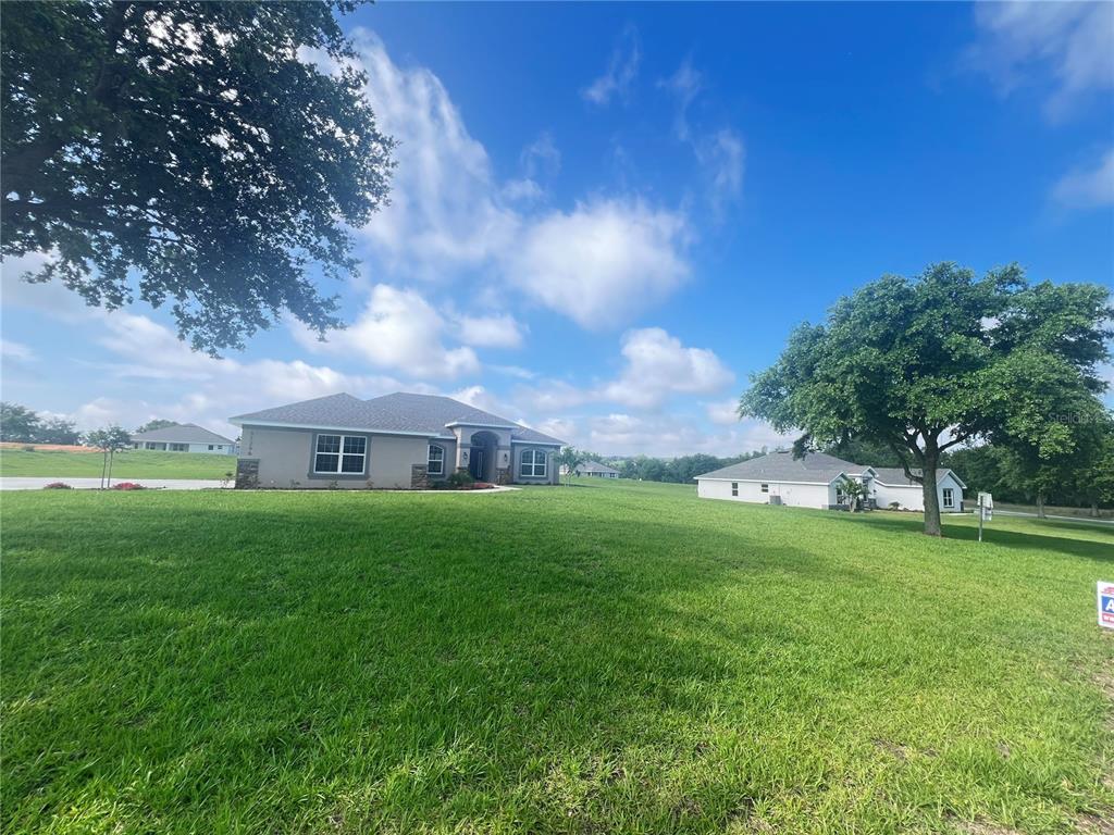 A grassy lot with a large tree and a house in the background — 37298 HIDDEN VIEW CIRCLE, DADE CITY, FL
