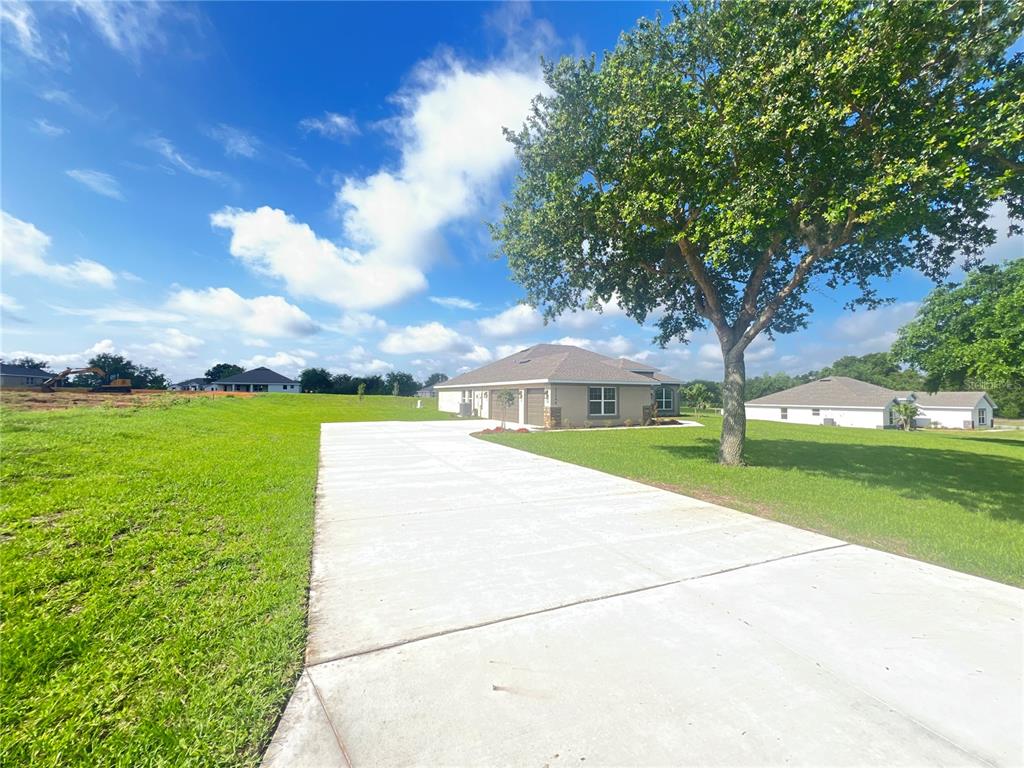 A tan single-story house with a two-car garage and a large concrete driveway — 37298 HIDDEN VIEW CIRCLE, DADE CITY, FL