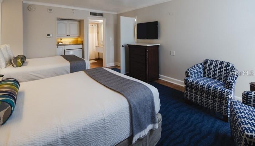 A hotel room features two beds, a small kitchenette, a dresser with a television, and chairs — 5500 GULF BOULEVARD UNIT 2249, ST PETE BEACH, FL