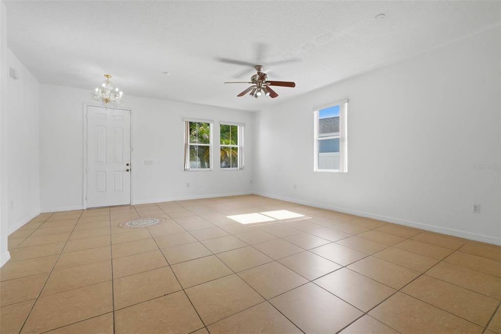 An empty room with white walls, tan tile flooring, a ceiling fan, and three windows — 2830 PAYNES PRAIRIE CIRCLE, KISSIMMEE, FL