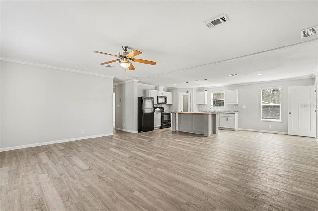 An open-concept living room and kitchen with light wood-look flooring and a central island — 23950 BASS ROAD, ASTOR, FL