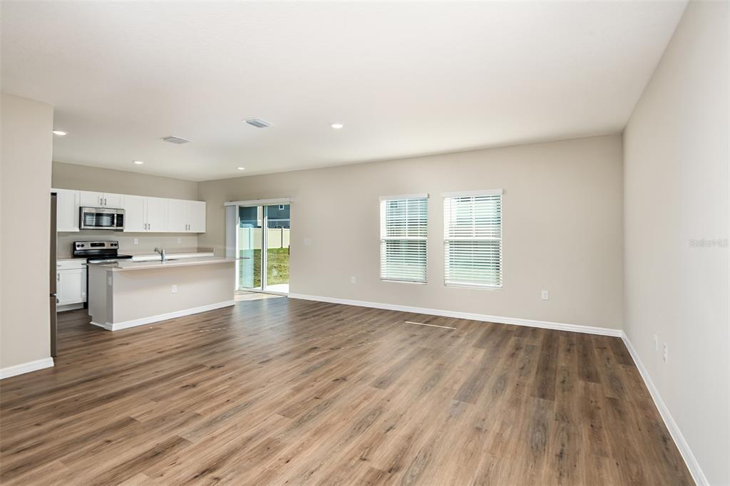 An open-concept kitchen and living area features white cabinetry, a breakfast bar, and wood-look flooring — 1589 SAGE AVENUE, HAINES CITY, FL