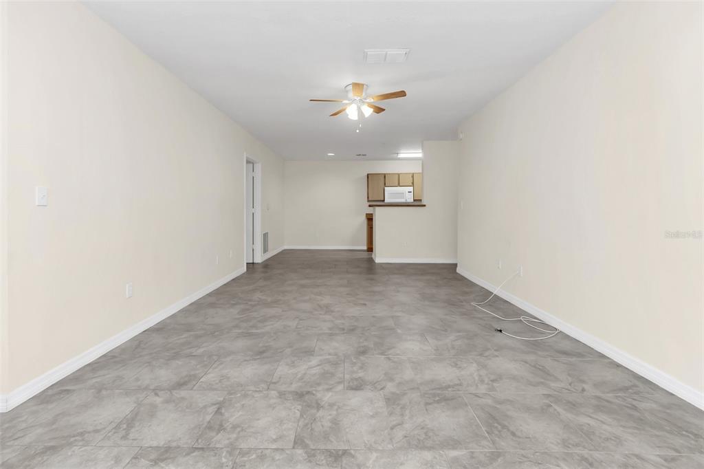 An open-concept living area features gray tile flooring, beige walls, and a ceiling fan — 4328 S KIRKMAN ROAD UNIT 1311, ORLANDO, FL