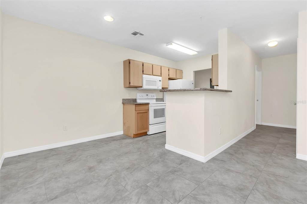 A kitchen with light wood cabinets, white appliances, and gray tile flooring — 4328 S KIRKMAN ROAD UNIT 1311, ORLANDO, FL