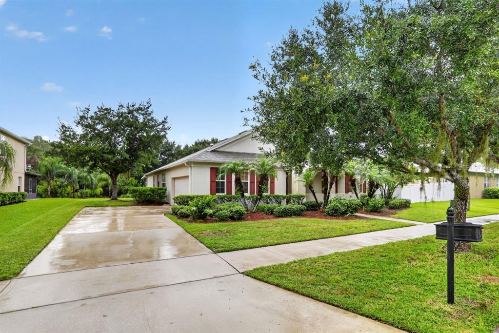 A single-story house with a concrete driveway, green lawn, and mature trees in the yard — 3730 CEDAR HAMMOCK TRAIL, ST CLOUD, FL