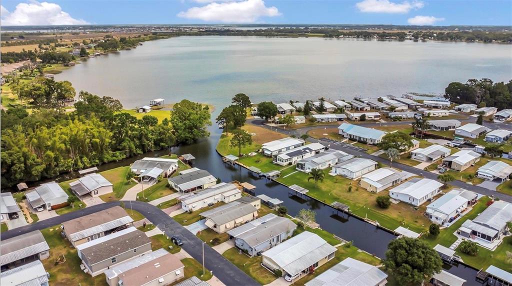 An aerial view shows a waterfront mobile home community with a canal leading to a lake — 119 JANA CIRCLE, AUBURNDALE, FL