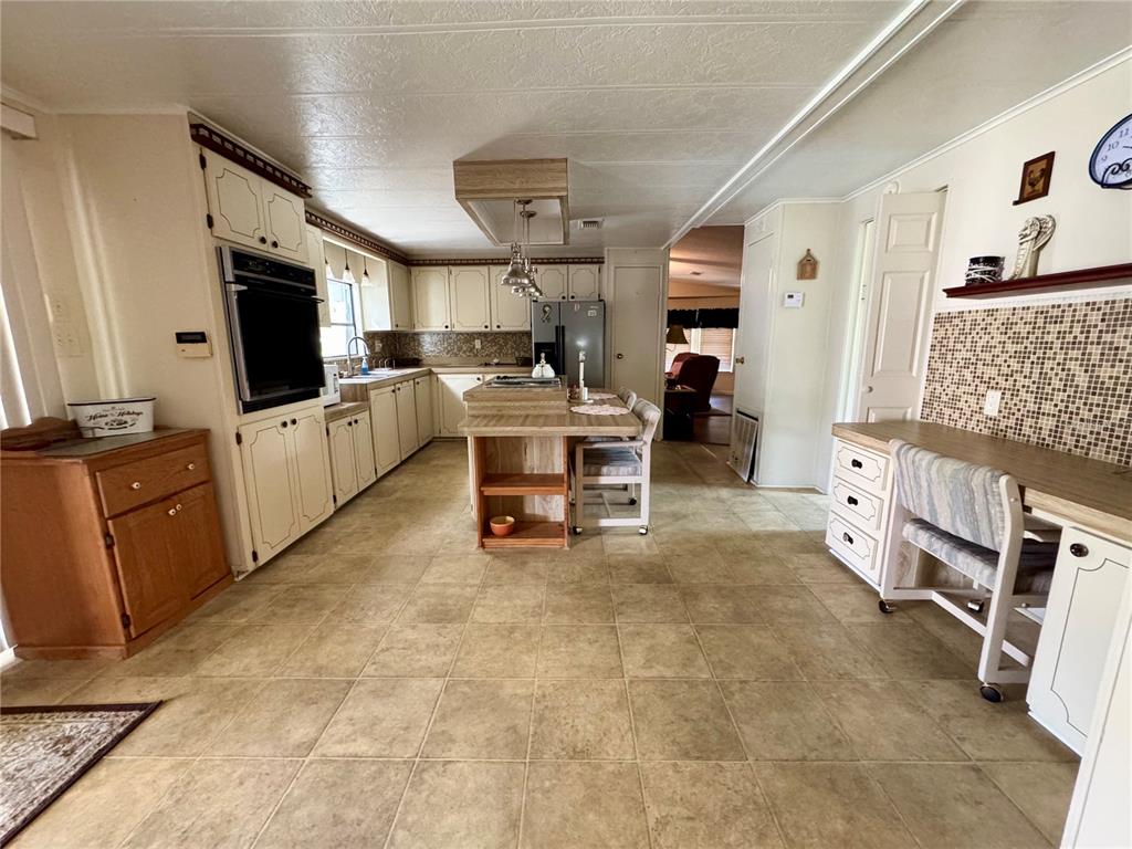 A kitchen features light-colored cabinetry, a central island, tile flooring, and a built-in wall oven — 119 JANA CIRCLE, AUBURNDALE, FL