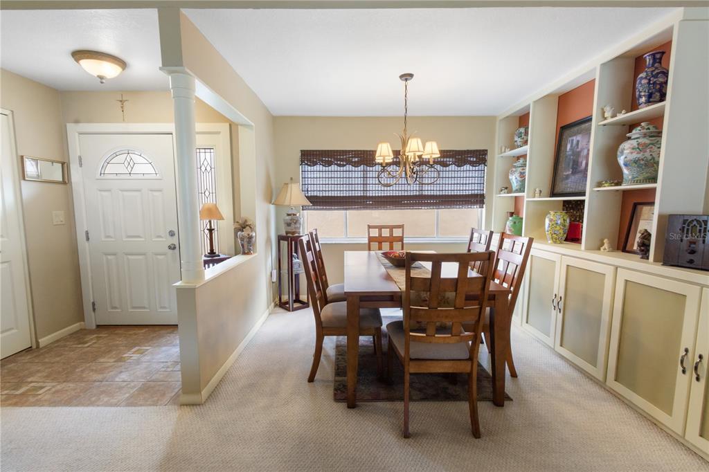 A dining room features a wooden table, chairs, built-in shelving, and an adjacent entryway — 111 LAS FLORES, WINTER HAVEN, FL