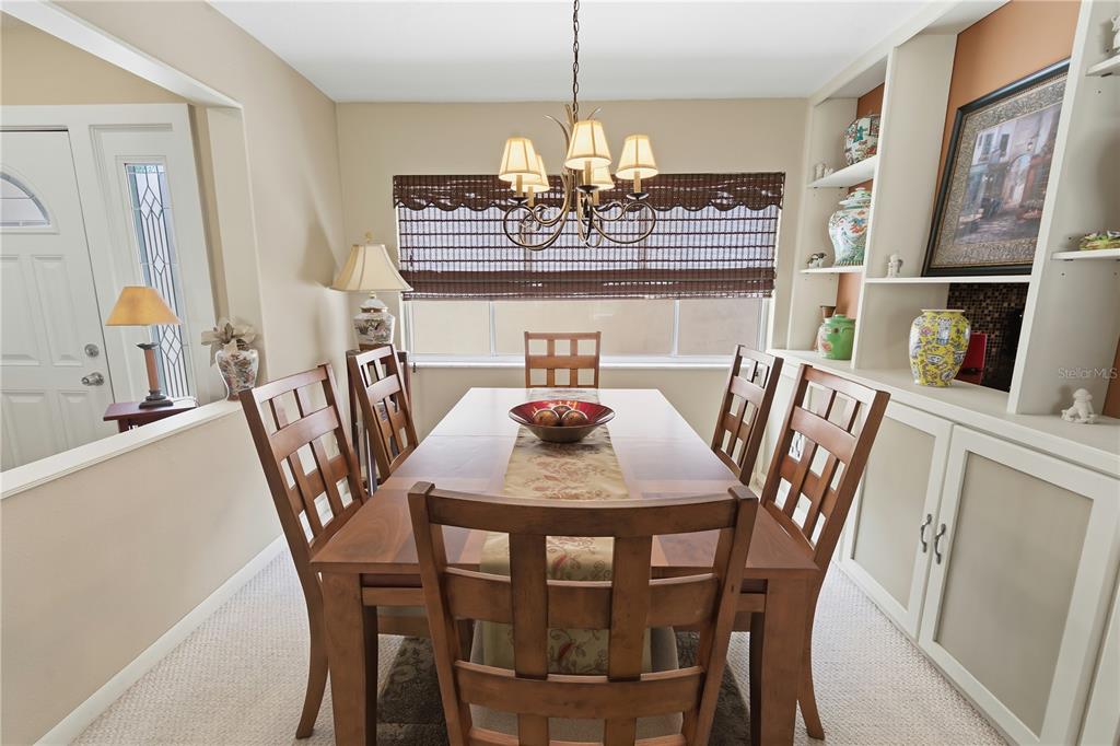A dining room features a wooden table with six chairs, a chandelier, and built-in shelving — 111 LAS FLORES, WINTER HAVEN, FL
