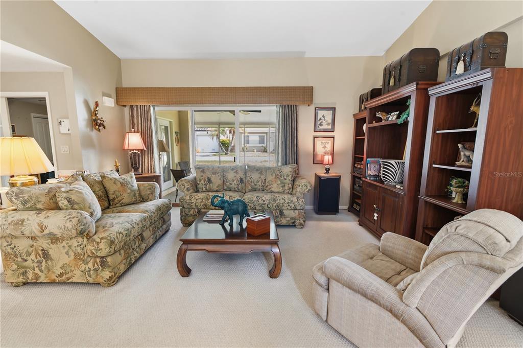 A living room features floral sofas, a wooden coffee table, and large wooden shelving units — 111 LAS FLORES, WINTER HAVEN, FL