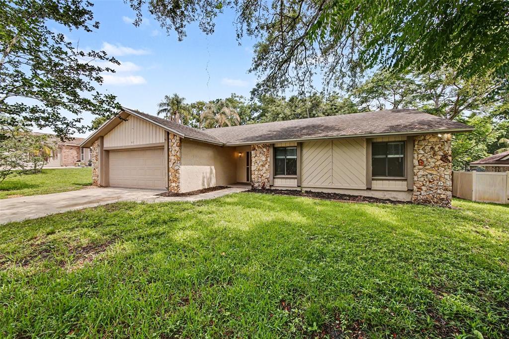 A single-story house with a stone facade, tan siding, and a two-car garage — 612 HEATHER BRITE CIRCLE, APOPKA, FL