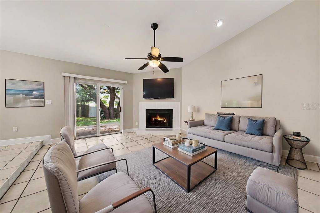 A living room features a fireplace, a ceiling fan, tile flooring, and a sliding glass door — 612 HEATHER BRITE CIRCLE, APOPKA, FL