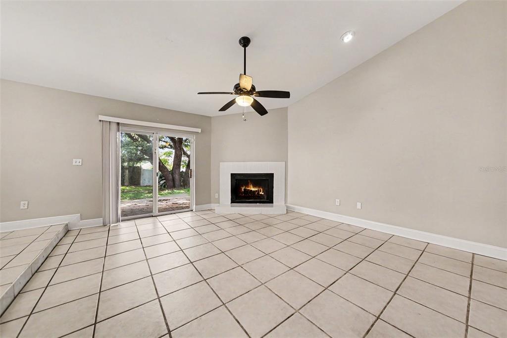 A living room with tile flooring, a fireplace, a ceiling fan, and sliding glass doors — 612 HEATHER BRITE CIRCLE, APOPKA, FL