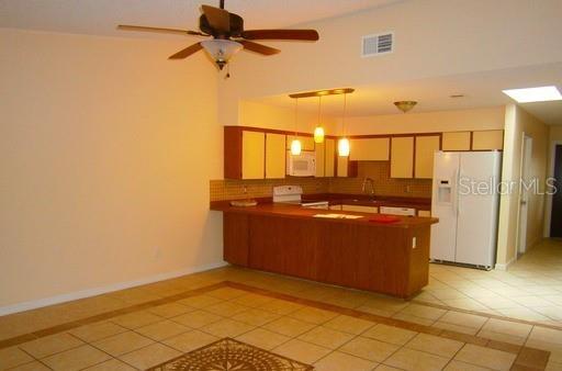 A kitchen with wood cabinets and a breakfast bar overlooks a tiled dining area — 4033 ANNA DRIVE, APOPKA, FL