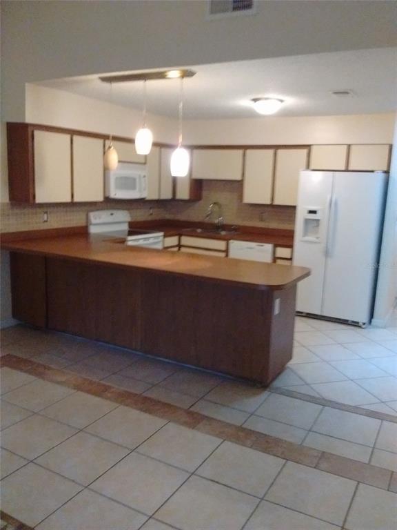 A kitchen features light-colored cabinets, a brown countertop, a white refrigerator, and tile flooring — 4033 ANNA DRIVE, APOPKA, FL
