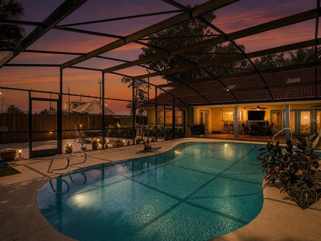 A screened-in swimming pool patio at dusk with a view of a house exterior — 2269 COUNTRY CLUB DRIVE, DELAND, FL