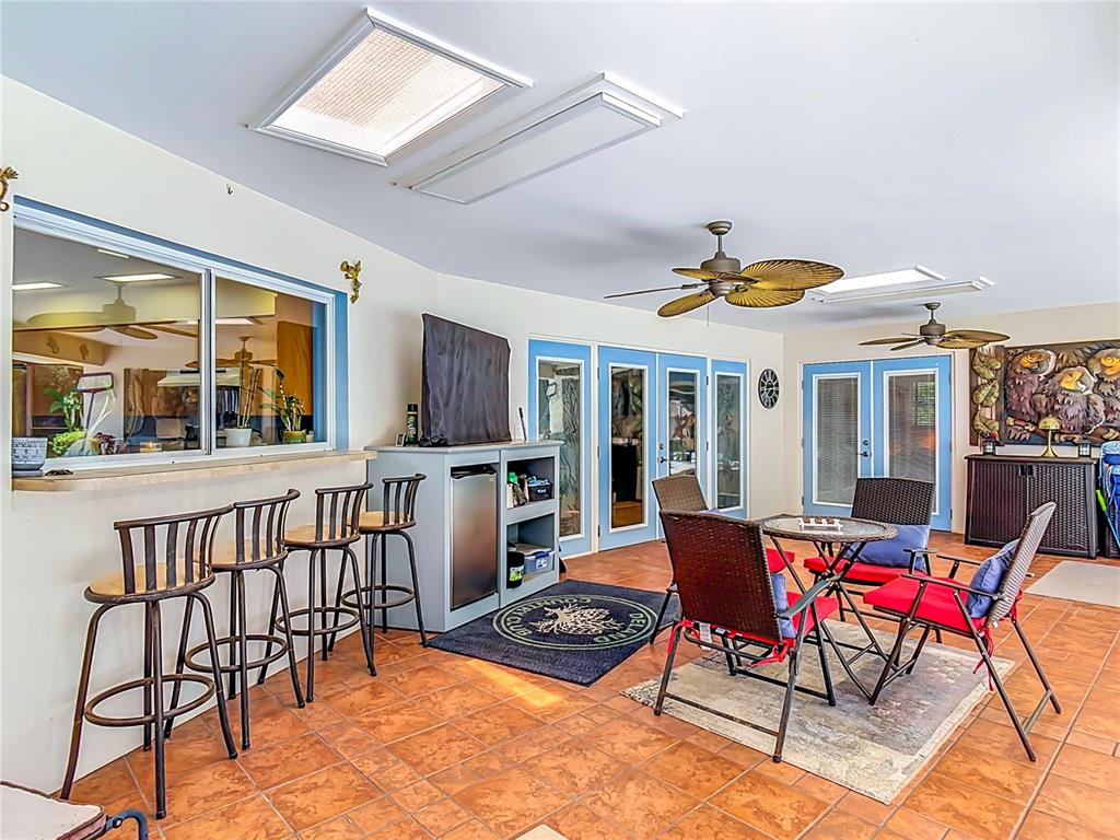 A sunroom features tile floors, a bar with stools, ceiling fans, and blue-framed doors — 2269 COUNTRY CLUB DRIVE, DELAND, FL
