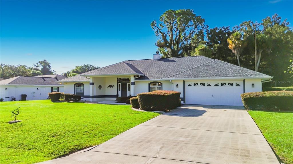A single-story house with a white exterior, a two-car garage, and a concrete driveway — 1281 N TIMUCUAN TRAIL, INVERNESS, FL
