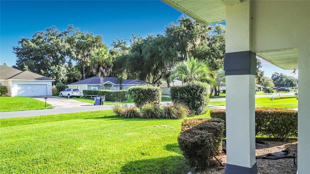 A view from a covered porch looking out over a suburban lawn and neighborhood houses — 1281 N TIMUCUAN TRAIL, INVERNESS, FL
