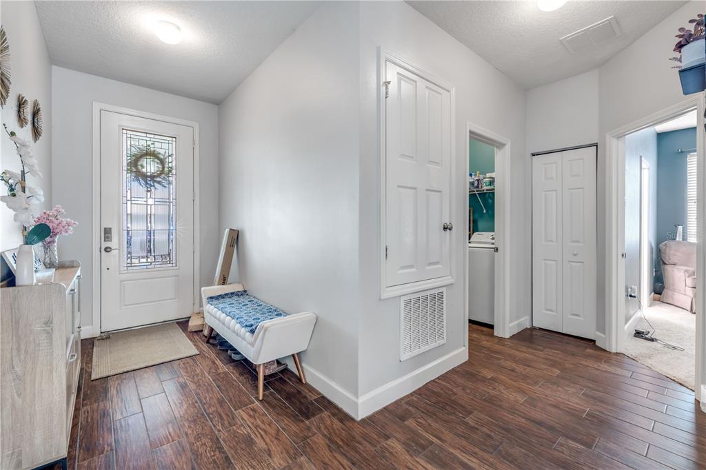 An entryway features wood-look tile flooring, a white front door, and a small bench — 54 LEVEE LANE, ORMOND BEACH, FL