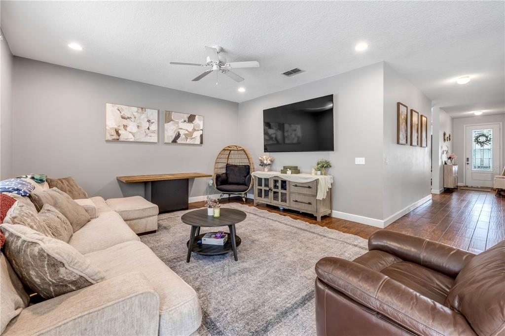 A living room features a large sectional sofa, a television, and a brown leather chair — 54 LEVEE LANE, ORMOND BEACH, FL