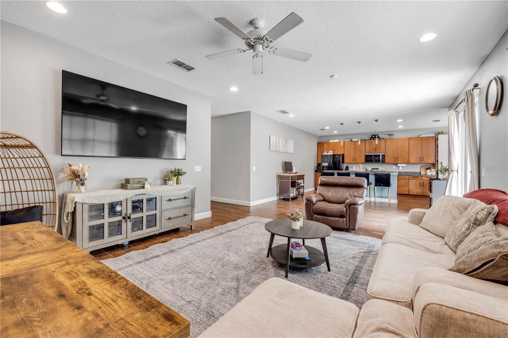 A living room with a large television, a beige sofa, and an open kitchen area — 54 LEVEE LANE, ORMOND BEACH, FL