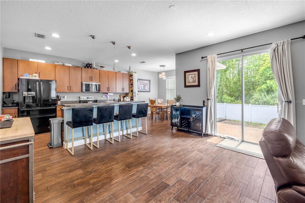 A kitchen with wood cabinets, a breakfast bar, and dining area overlooks a backyard patio — 54 LEVEE LANE, ORMOND BEACH, FL