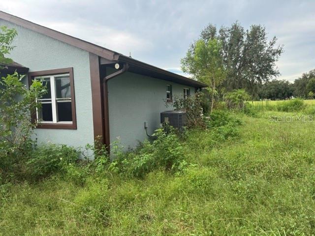 The exterior side of a light blue house with a window and an air conditioning unit — 2231 CR 543, SUMTERVILLE, FL