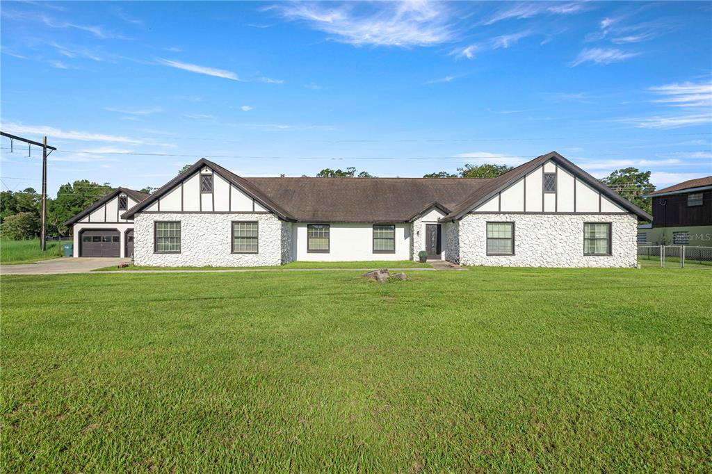 A single-story house with white stone siding, dark trim, and a large front lawn — 1166 SE 44TH AVENUE, OCALA, FL