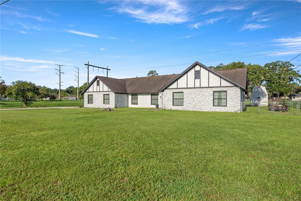 A single-story house with white stone siding and Tudor-style timber accents sits on a large lawn — 1166 SE 44TH AVENUE, OCALA, FL