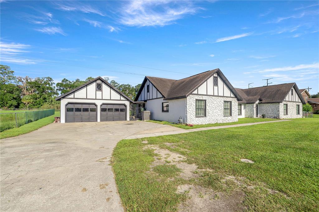 A white house with Tudor-style trim and a detached two-car garage sits on a lawn — 1166 SE 44TH AVENUE, OCALA, FL