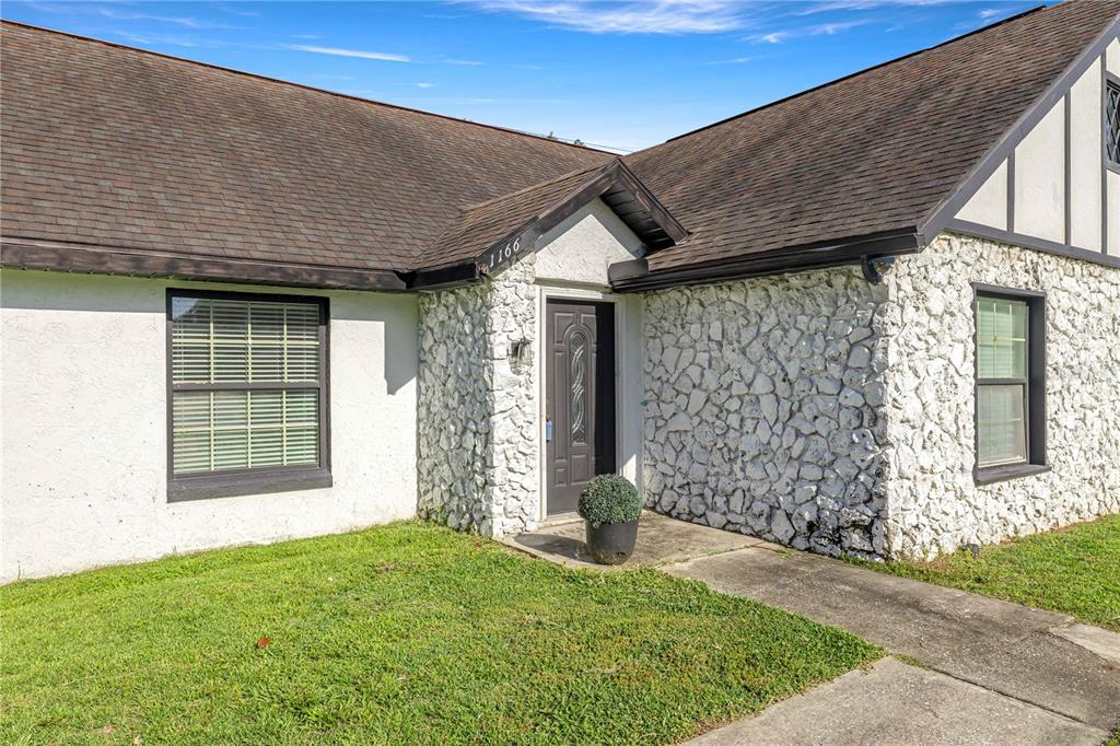 The exterior of a house features white stucco, stone veneer, and a dark shingled roof — 1166 SE 44TH AVENUE, OCALA, FL