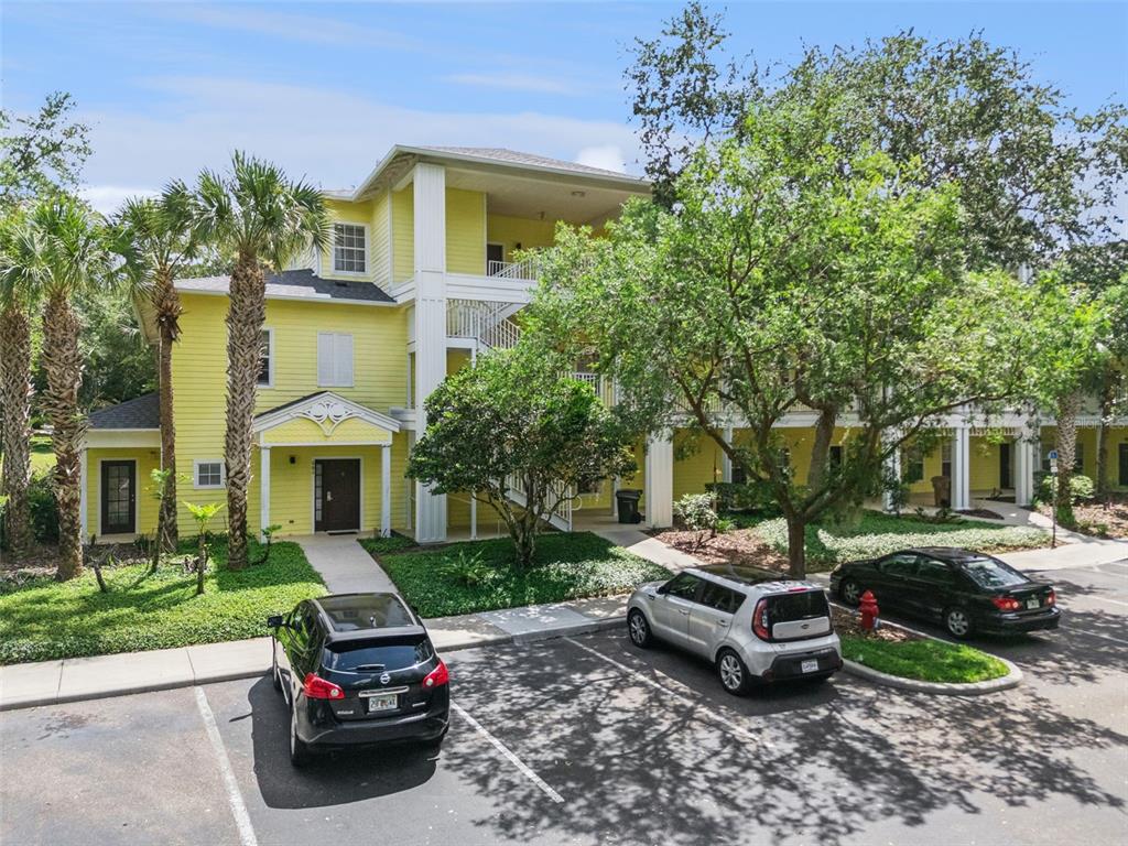 A three-story yellow apartment building with a parking lot in the foreground — 313 LUCAYA LOOP, DAVENPORT, FL
