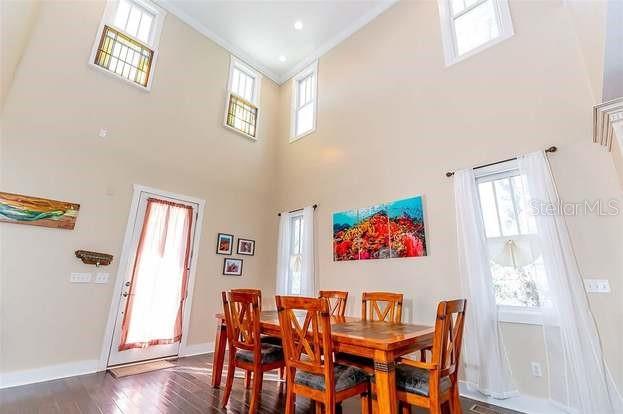 A dining room with a wooden table, chairs, high ceilings, and multiple windows — 204 VIRGINIA AVENUE, STEINHATCHEE, FL