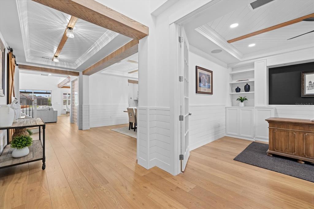 A bright home interior features wood floors, white wainscoting, exposed ceiling beams, and a home office — 3214 ANCHOR BAY TRAIL, BRADENTON, FL
