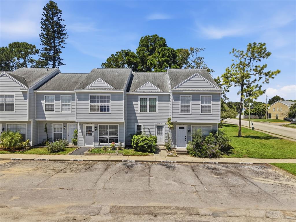 A two-story gray townhouse exterior with a paved parking lot in the foreground — 6710 121ST AVENUE UNIT 11, LARGO, FL