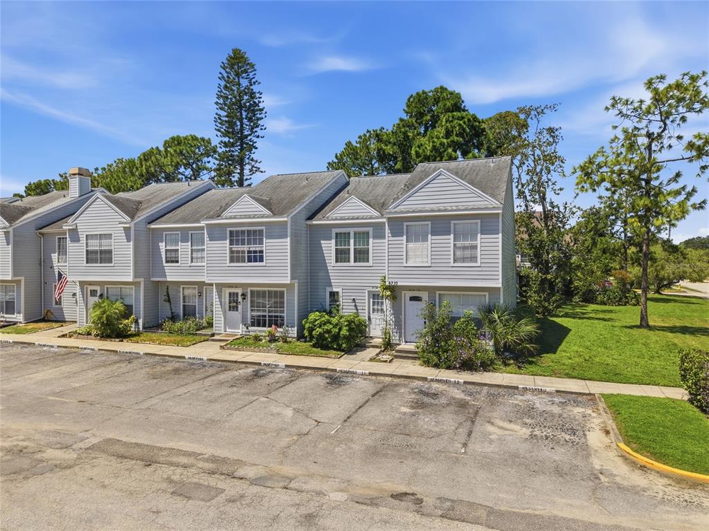 A multi-unit townhouse building with light gray siding sits behind a paved parking lot — 6710 121ST AVENUE UNIT 11, LARGO, FL